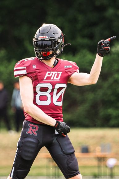 Ein Footballspieler in rot-schwarzer Uniform zeigt mit dem Finger.