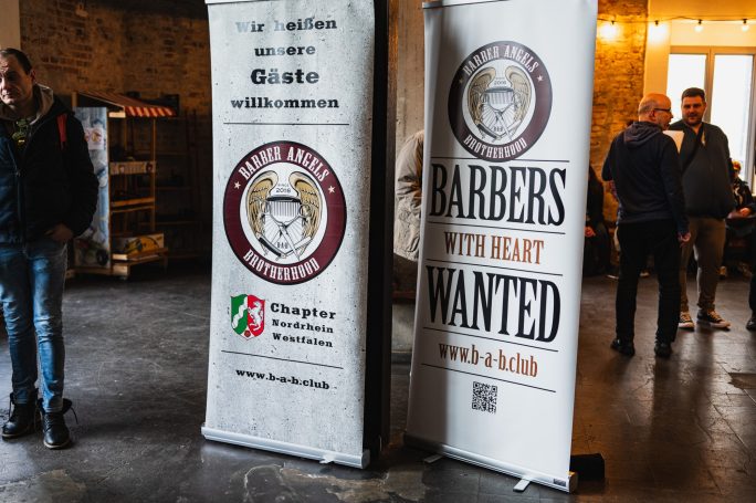 Zwei Standbanner mit Werbung für Friseure und Informationen über eine Veranstaltung.