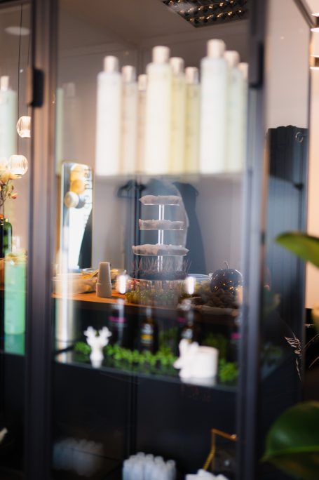 Regal mit Pflegeprodukten, Pflanzen und dekorativen Elementen im modernen Salon.