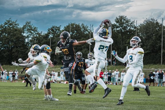 Spielszene im American Football: Spieler fangen einen Pass auf dem Spielfeld.