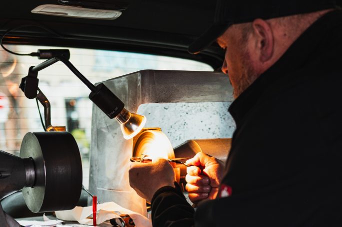 Mann arbeitet an einer Maschine, während er einen Gegenstand beleuchtet.
