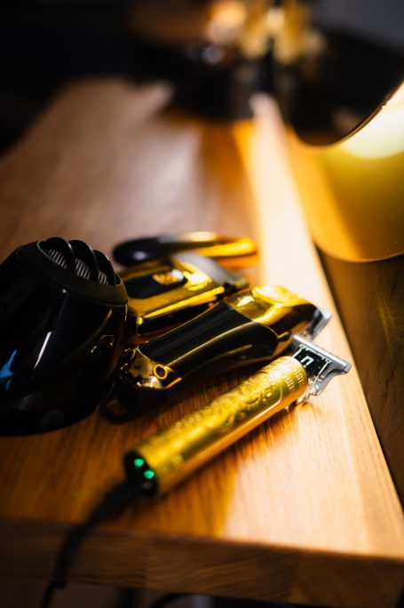 Frisurwerkzeuge in Goldtönen auf einem Tisch, mit einem Fokus auf den Haarschneider.