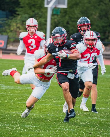 Spielszene im American Football mit einem Spieler, der einen Gegner am Boden schnappt.