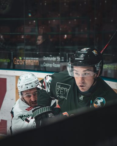 Eishockeyspieler kämpft um den Puck in einem intensiven Spielmoment.