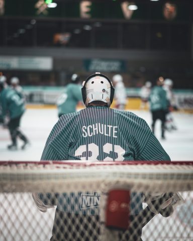 Eishockeyspieler mit Rückennummer 33 beobachtet das Spiel von der Torlinie aus.
