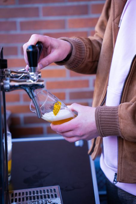 Ein Mann zapft ein Bier mit einem Schuss Orange in ein Glas.