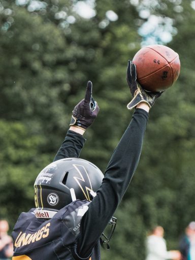 Spieler hebt die Hand mit einem Football, bereit zum Pass oder Touchdown.