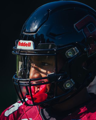 Ein Footballspieler mit Helm und Mundschutz, konzentriert beim Spiel.