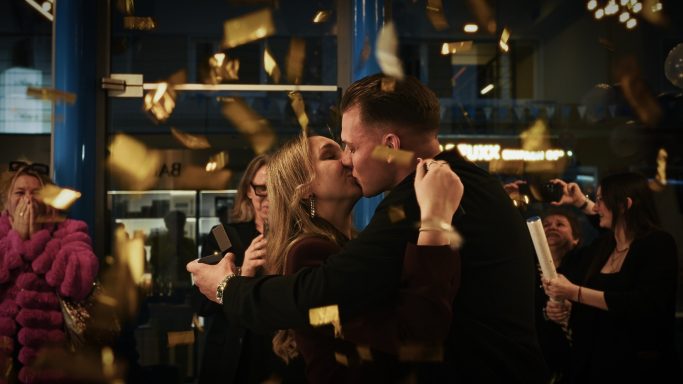 Ein Paar küsst sich umgeben von Konfetti bei einer Feier.