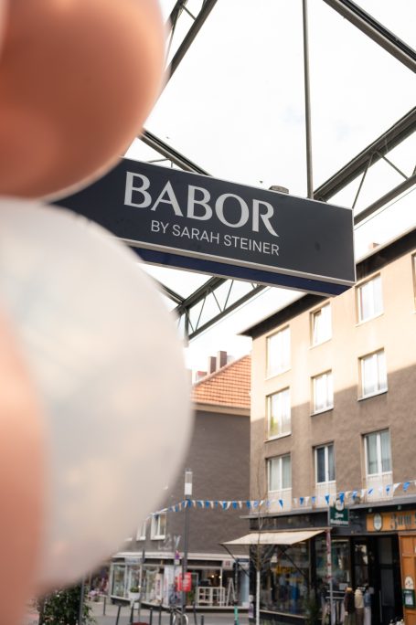 Sicht auf ein Geschäftsschild von "BABOR" in einer belebten Straße.