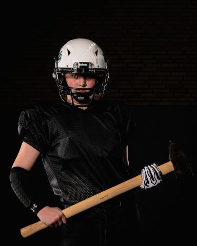 Kraftsportler in schwarzer Ausrüstung hält einen Hammer, trägt Helm und Schutzausrüstung.