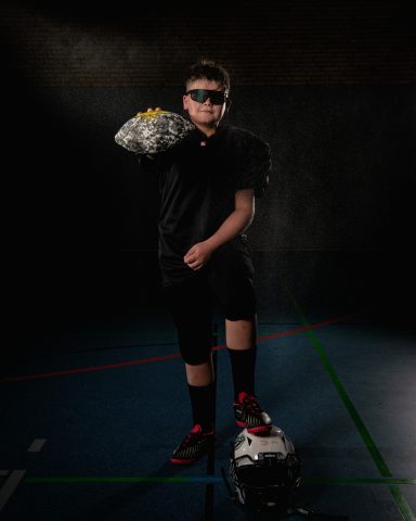 Junge in Sportkleidung hält eine spritzende Wasserflasche in der Hand.