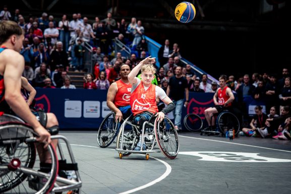 Junge Spieler im Rollstuhl-Basketball wirft den Ball in einem Wettkampf.