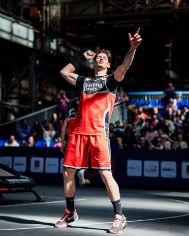 Ein Spieler in roter Sportkleidung feiert nach einem Punktgewinn in einer Halle.