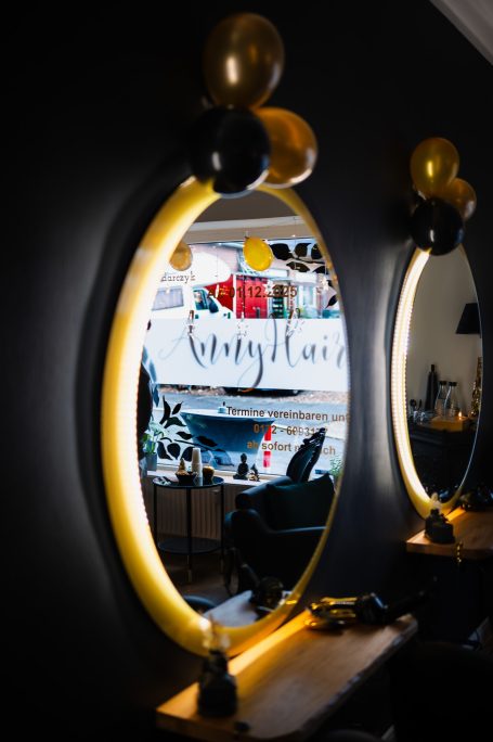 Spiegel mit gelben und schwarzen Luftballons, Friseursalon im Hintergrund.