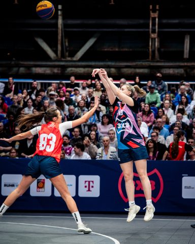 Zwei Spielerinnen im Basketballspiel, eine wirft, die andere versucht zu blocken.