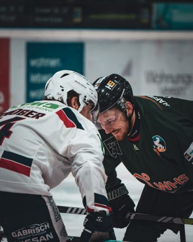 Zwei Eishockeyspieler stehen in einer Ecke und bereiten sich auf das Face-off vor.