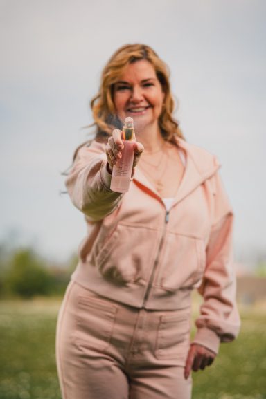 Frau in sportlicher Kleidung, lächelt und hält etwas in der Hand.