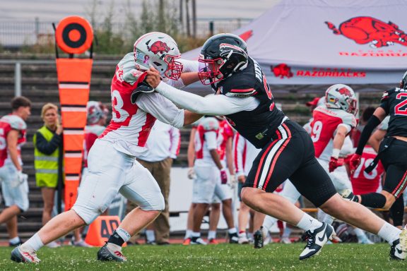 Zwei American-Football-Spieler im Wettkampf um den Ball auf dem Spielfeld.